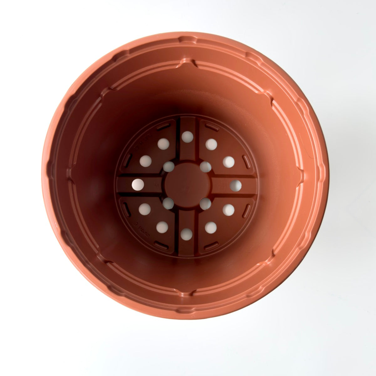 Terracotta-colored planter with drainage holes on a white background